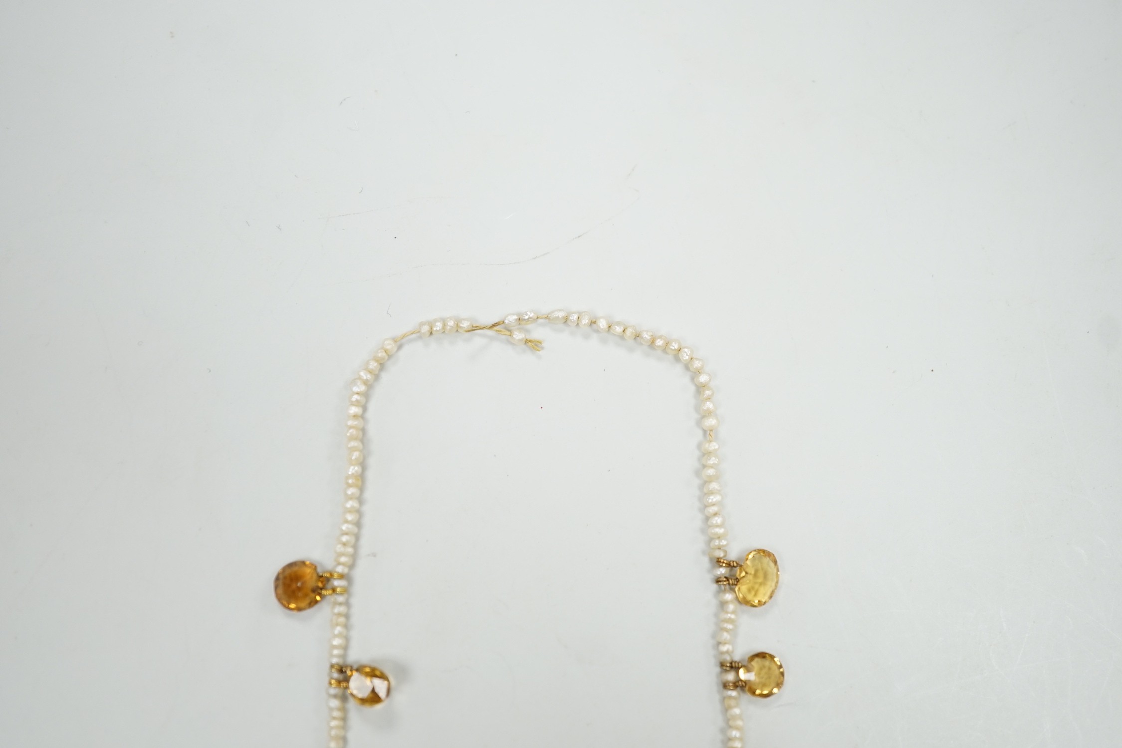 An Edwardian twenty one graduated oval cut citrine set seed pearl necklace (a.f) clasp loose, approx. 34cm.